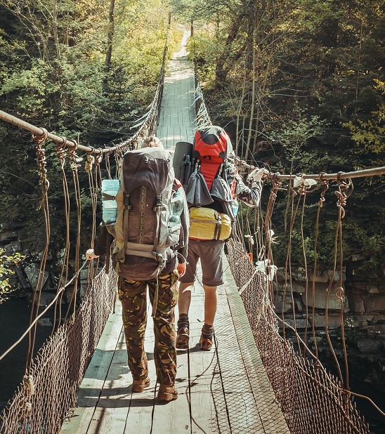 Backpackers crossing a hanging bridge on a sunny day
