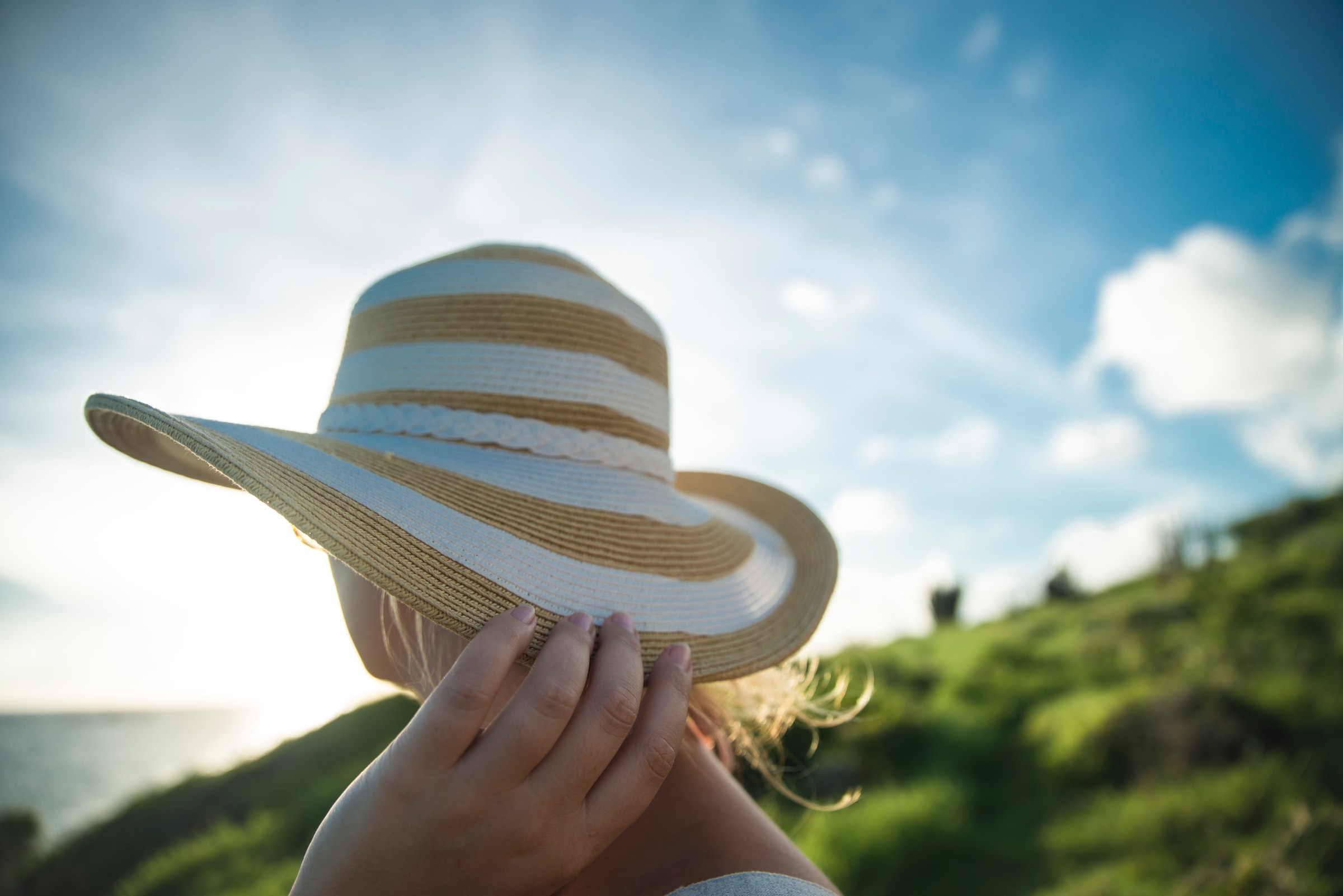Woman in sun hat looks out over the ocean on vacation
